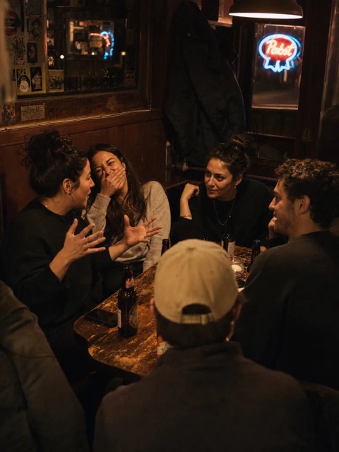 A group crowded into a bar booth, deep in a story